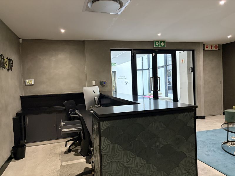 Modern commercial reception area featuring a custom built-in desk, polished concrete floors, and glass entry doors with professional lighting.