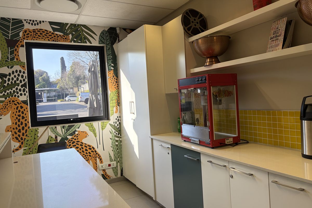 A functional kitchenette area featuring built-in cabinetry, stone countertops, a yellow tiled backsplash, and a window with exterior views.