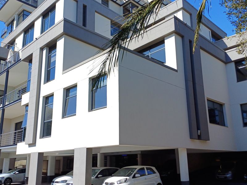 Modern multi-story office building facade featuring clean architectural lines, large windows, private balconies, and a ground-level covered parking area.