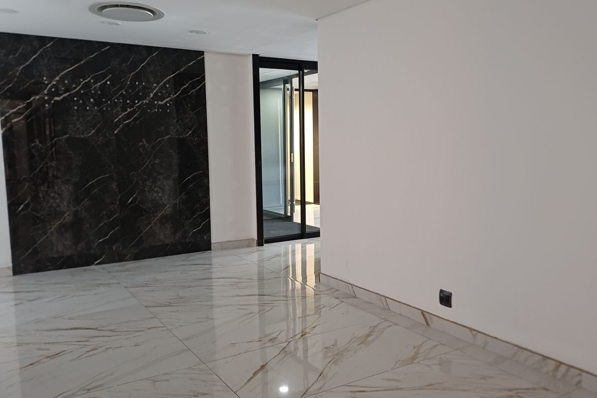 Modern office space featuring polished marble-look floor tiles, a striking black marble feature wall, and contemporary recessed lighting.