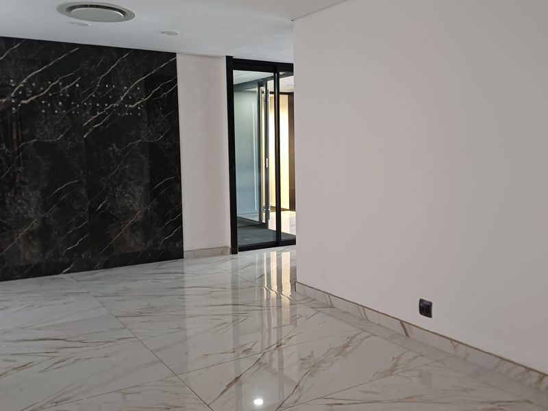 Modern office space featuring polished marble-look floor tiles, a striking black marble feature wall, and contemporary recessed lighting.