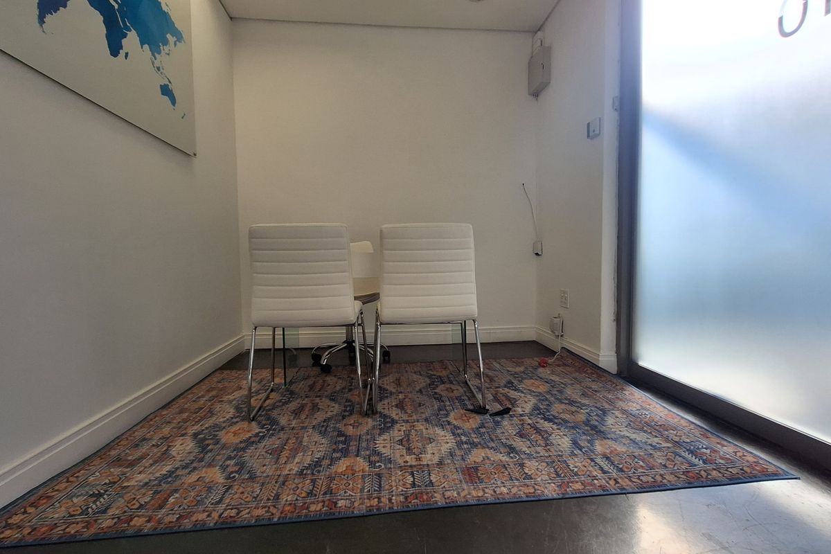A compact office space featuring a frosted glass entry door, neutral walls, and polished flooring, suitable for a private meeting or workspace.
