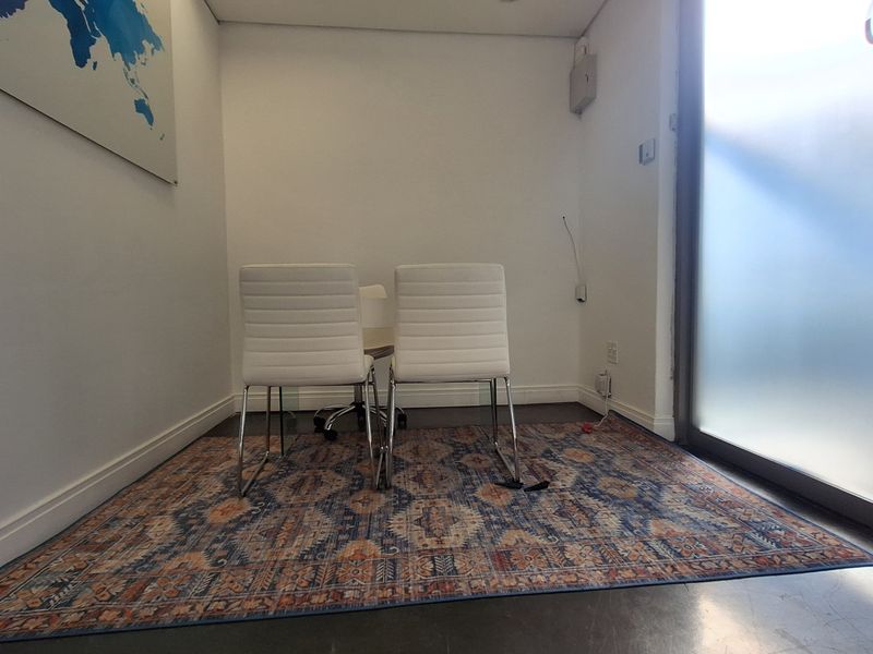 A compact office space featuring a frosted glass entry door, neutral walls, and polished flooring, suitable for a private meeting or workspace.