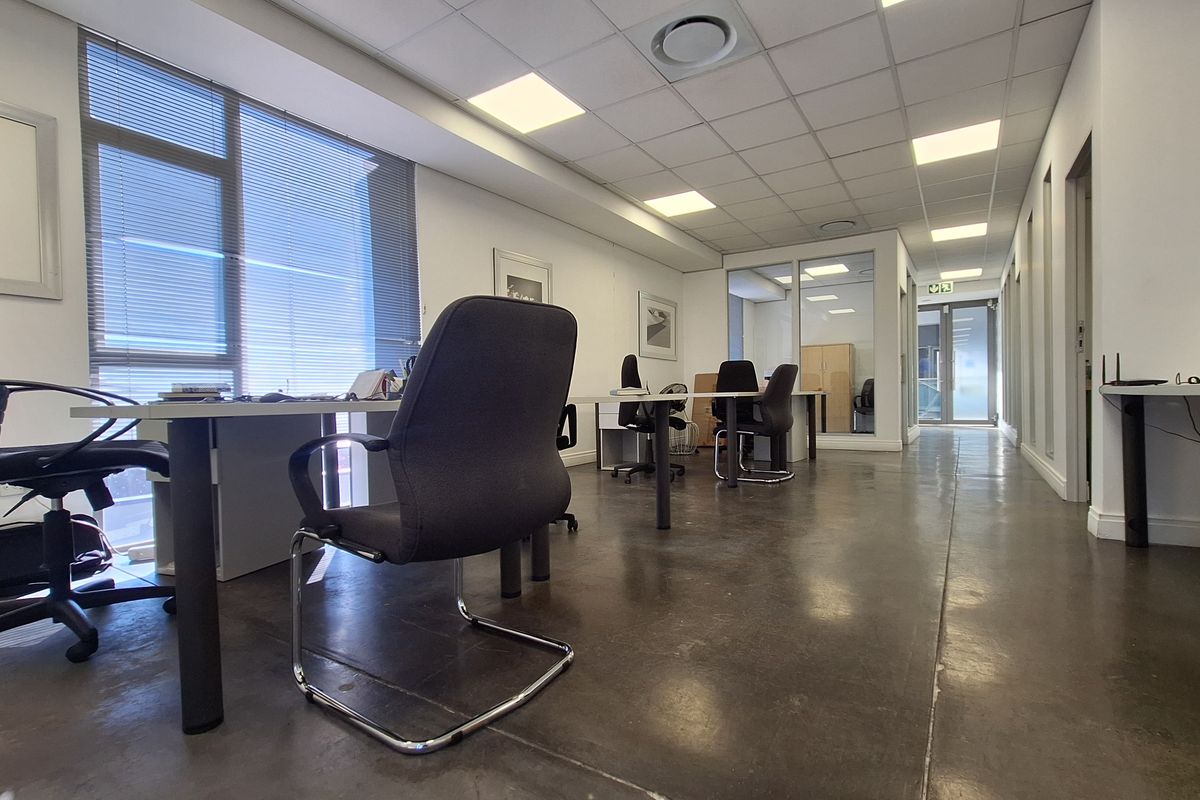Modern open-plan office space featuring polished concrete floors, suspended ceilings with recessed lighting, and glass partitioning for a professional work environment.
