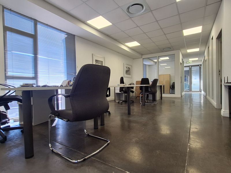 Modern open-plan office space featuring polished concrete floors, suspended ceilings with recessed lighting, and glass partitioning for a professional work environment.