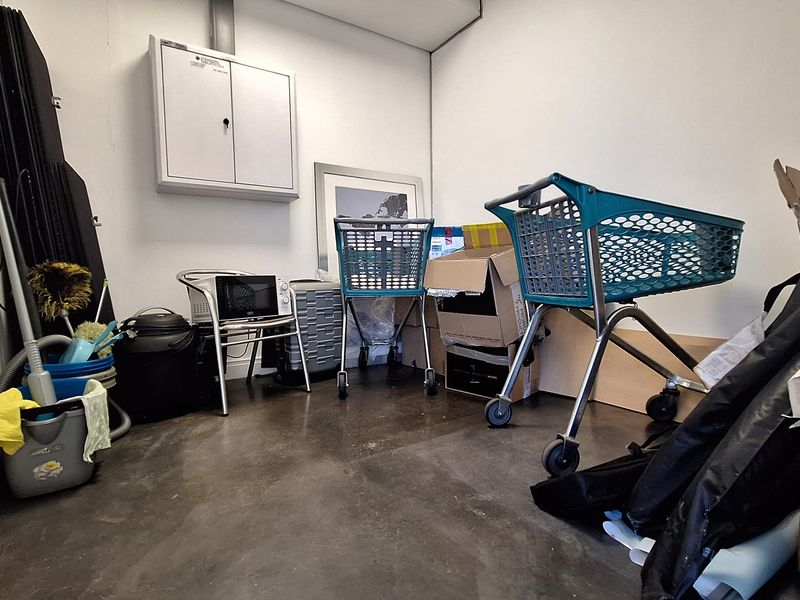 A functional utility or storage space featuring concrete flooring and a wall-mounted storage cabinet, currently utilized for miscellaneous storage.