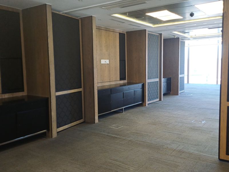 A spacious, modern office area featuring high-quality wood paneling, built-in cabinetry, recessed ceiling lighting, and carpeted flooring, offering a professional and clean workspace environment.