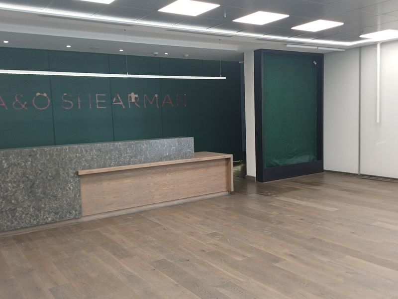 Modern office reception area featuring a custom built-in desk, hardwood flooring, and professional recessed ceiling lighting.