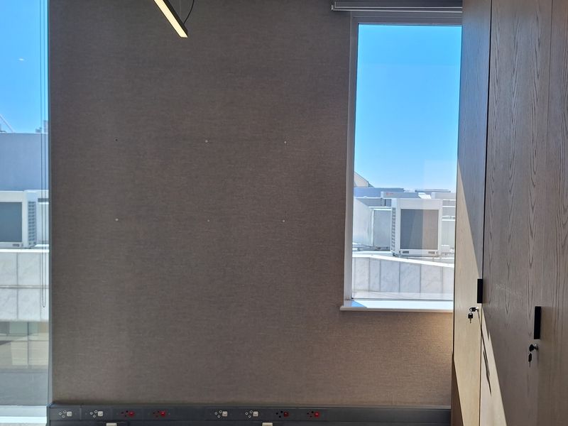 A modern, empty office space featuring built-in wooden cabinetry, linear lighting, and extensive power and data connectivity points.