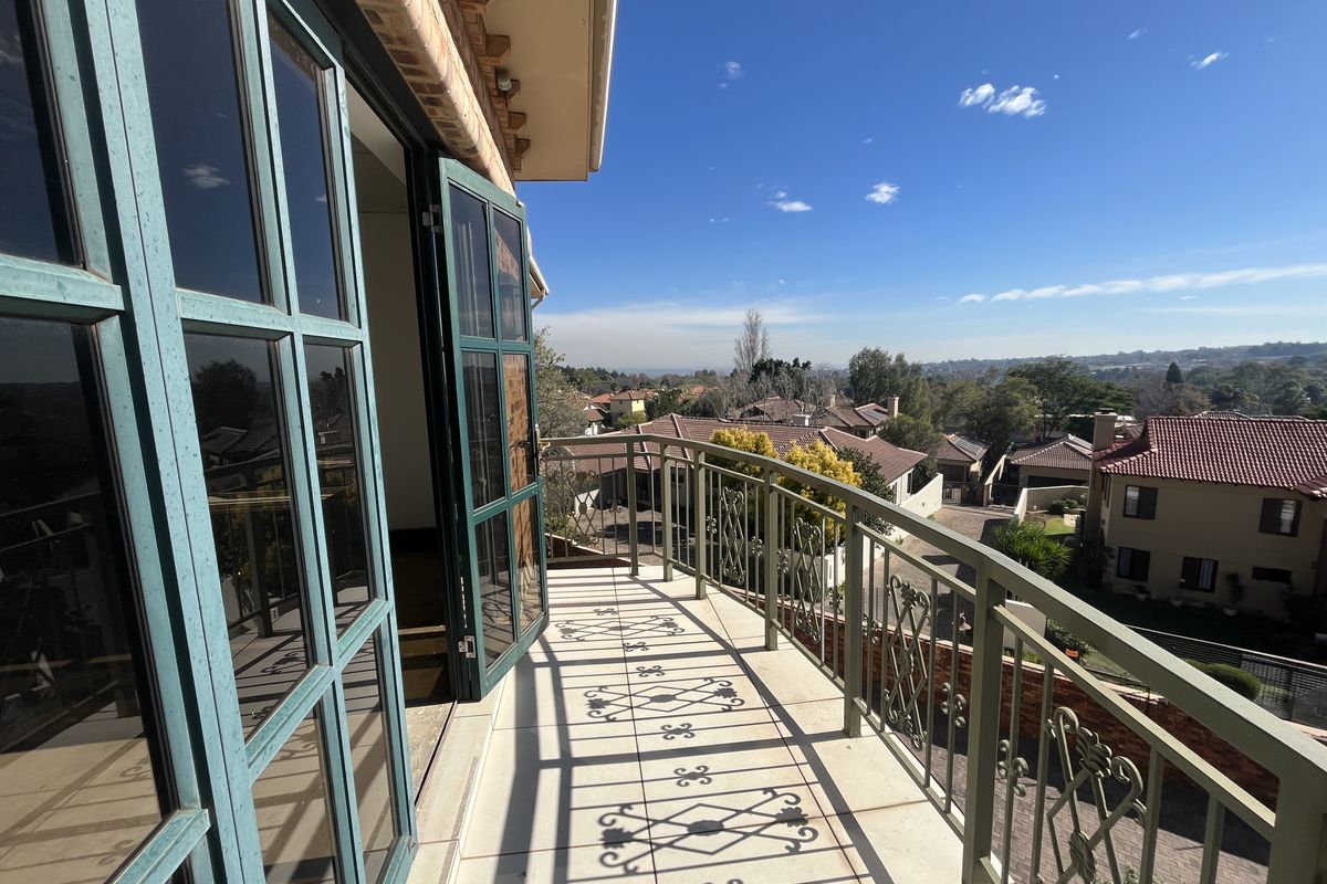 A spacious balcony featuring a decorative wrought iron balustrade, tiled flooring, and expansive views of the surrounding residential neighborhood.
