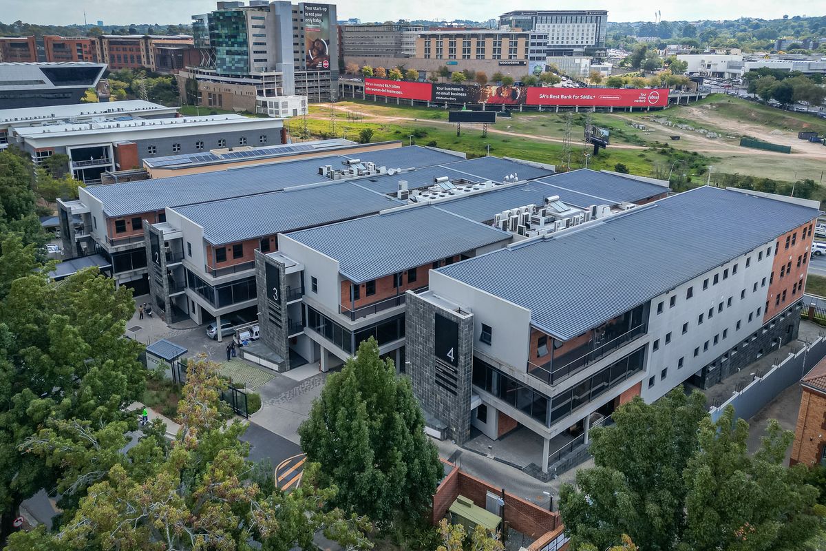 Aerial view of a modern multi-building office park complex featuring metal roofing, integrated HVAC systems, and landscaped surroundings in a commercial district.