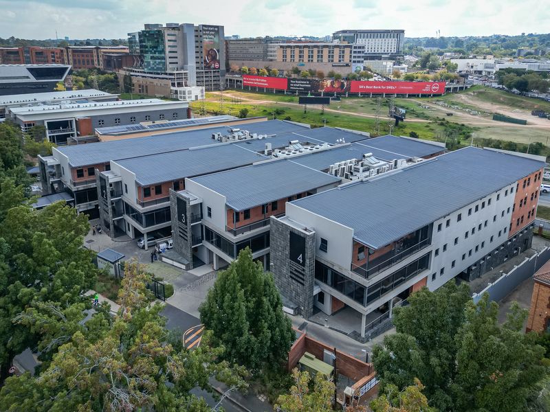 Aerial view of a modern multi-building office park complex featuring metal roofing, integrated HVAC systems, and landscaped surroundings in a commercial district.