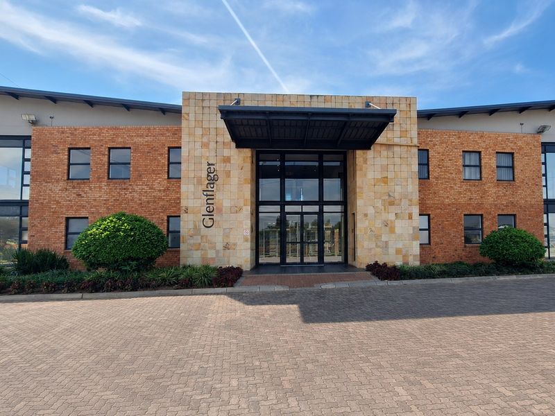 Front elevation of the Glenflager office building featuring a combination of brick and stone cladding with a prominent glass entrance and paved driveway.