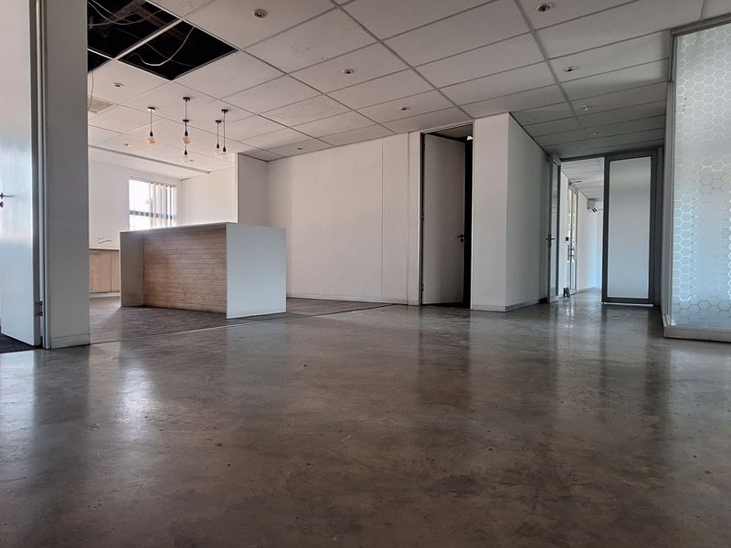 Open-plan office space featuring polished concrete floors, a built-in reception counter, and glass partitioning, currently requiring ceiling repairs.