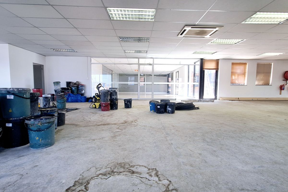 Spacious open-plan office area featuring a suspended ceiling, recessed lighting, integrated air conditioning, and glass partitioning, currently undergoing renovation.