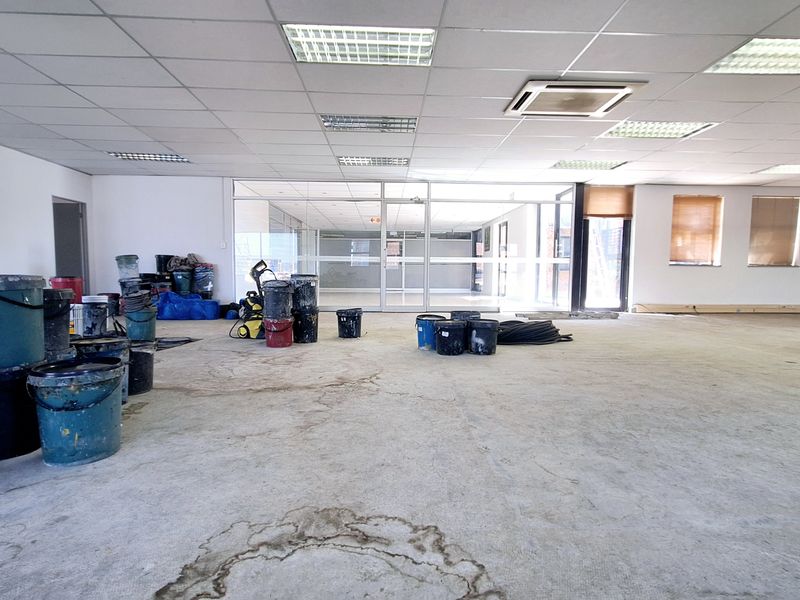 Spacious open-plan office area featuring a suspended ceiling, recessed lighting, integrated air conditioning, and glass partitioning, currently undergoing renovation.