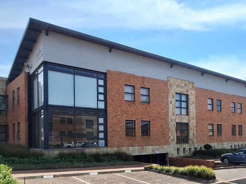 A professional multi-story office building featuring a combination of brick and stone facade, large glass windows, and an integrated underground parking entrance.