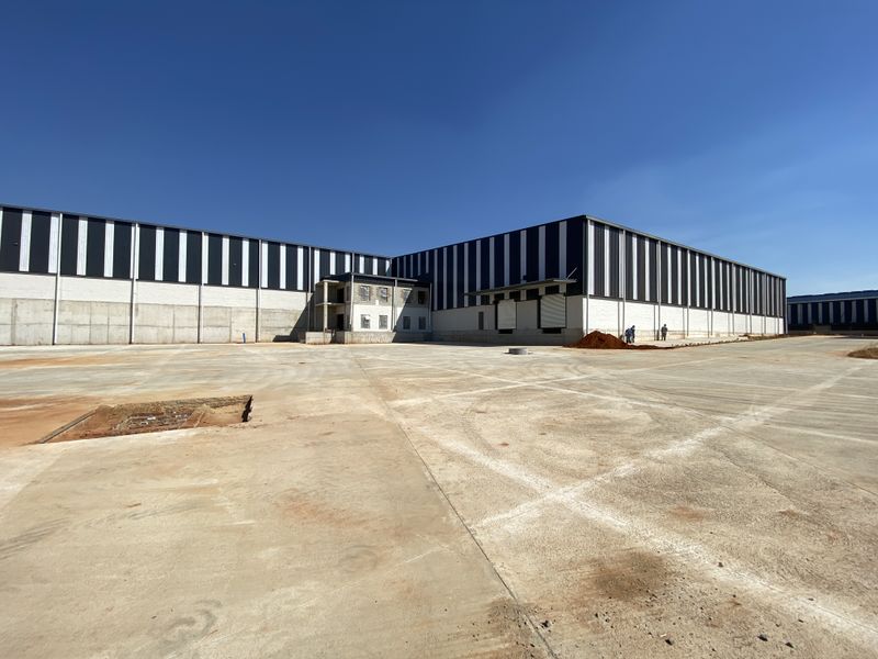 Large industrial warehouse facility featuring a expansive concrete yard, metal cladding exterior, and functional loading bay access.