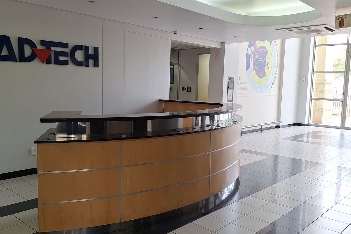 Professional office reception area featuring a curved built-in desk, modern tiled flooring, and bright, clean finishes suitable for a corporate environment.