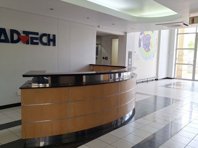 Professional office reception area featuring a curved built-in desk, modern tiled flooring, and bright, clean finishes suitable for a corporate environment.