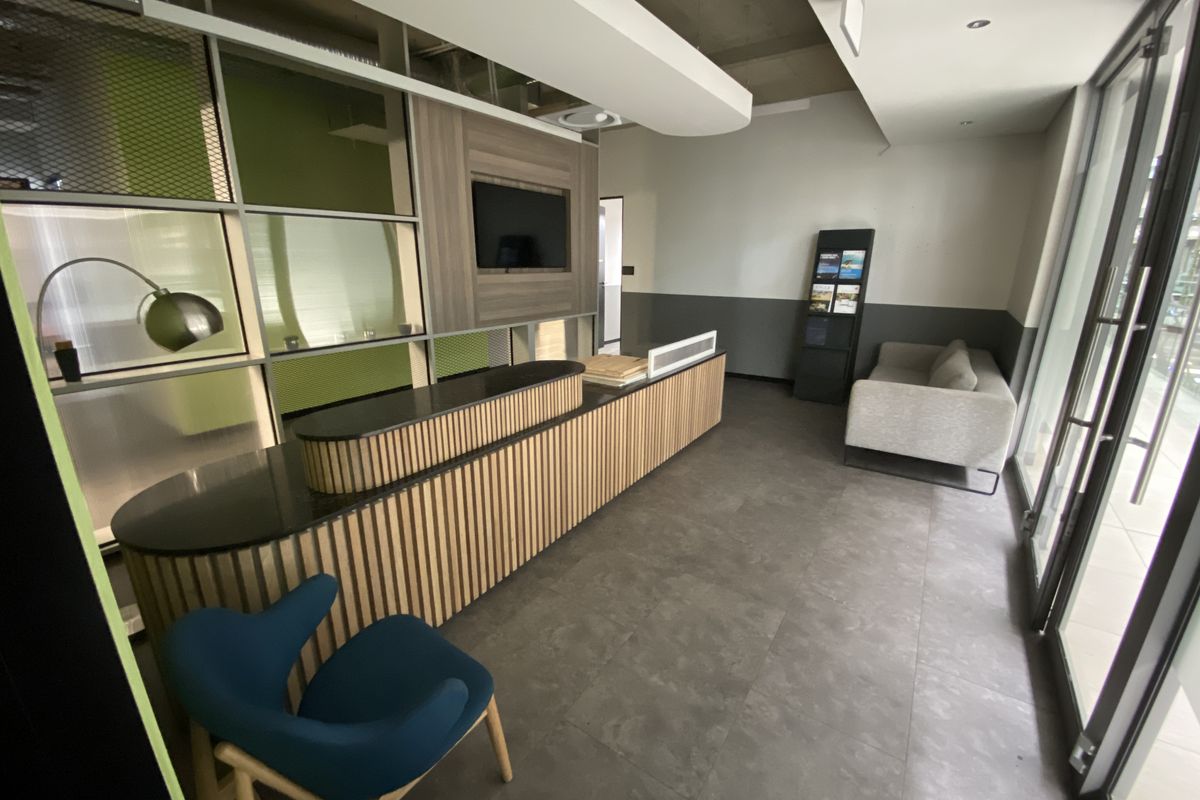 Modern office reception area featuring a custom built-in desk, integrated media display, and contemporary glass partitioning with professional tiled flooring.