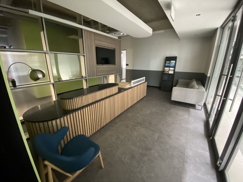 Modern office reception area featuring a custom built-in desk, integrated media display, and contemporary glass partitioning with professional tiled flooring.