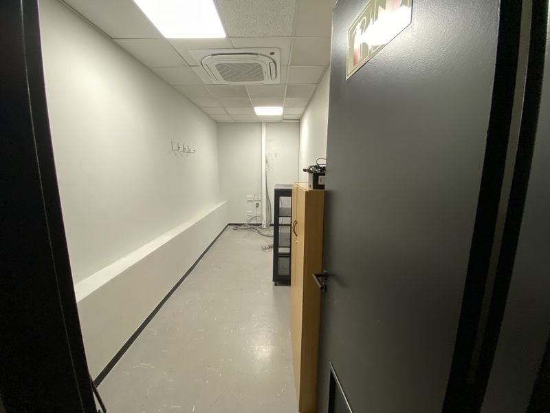 A functional utility or server room featuring a suspended ceiling, recessed lighting, ceiling-mounted air conditioning, and durable vinyl flooring.