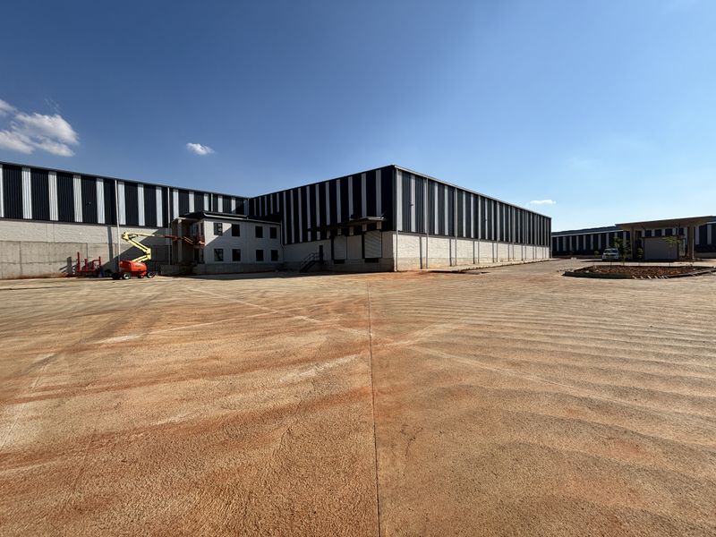 Large industrial warehouse facility featuring extensive concrete yard space, loading docks, and modern metal cladding construction.