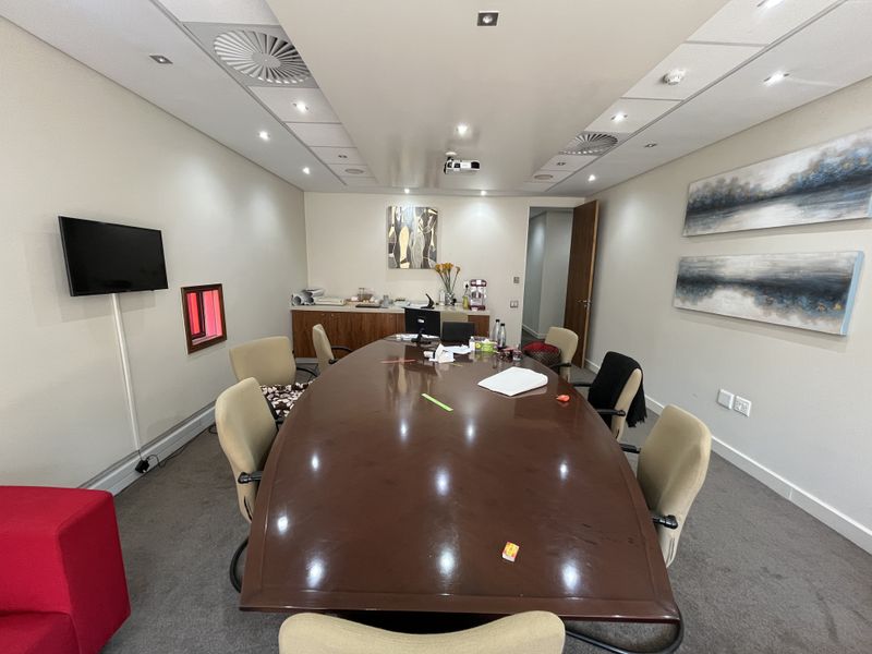 A professional office boardroom featuring a large central table, built-in cabinetry, recessed ceiling lighting, and integrated air conditioning systems.