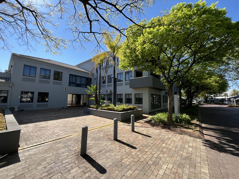 Front exterior view of a professional office building featuring paved access, mature landscaping, and a well-maintained facade.