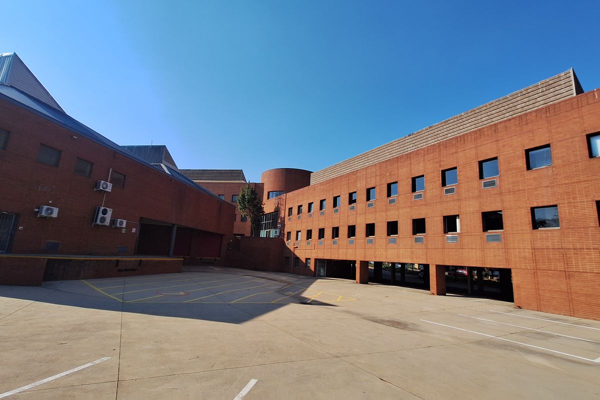 A wide-angle view of the industrial property's rear exterior, featuring a large concrete yard, brick facade, and integrated loading bay area.
