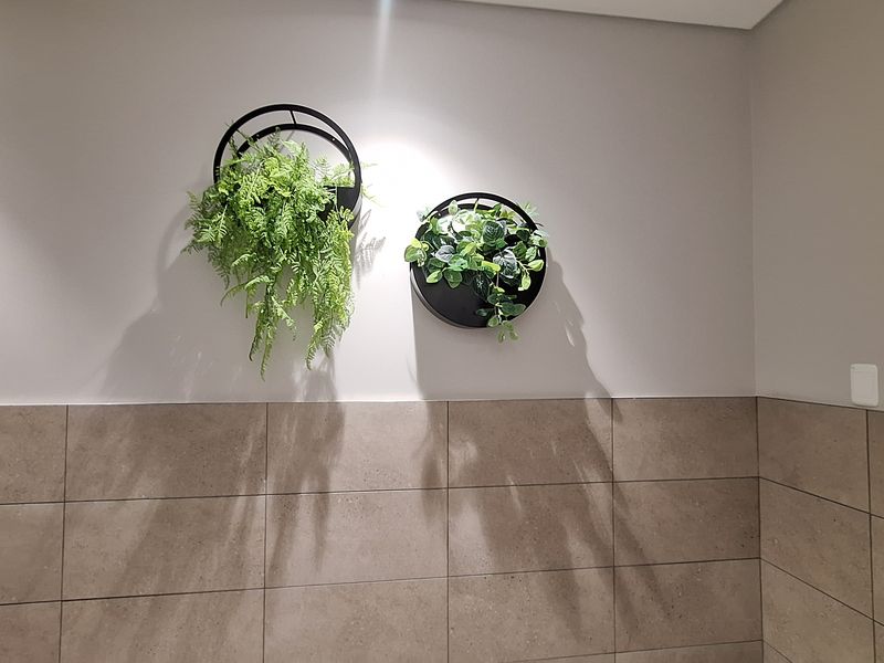 A neutral interior space featuring half-height tiled wall cladding and recessed ceiling lighting.