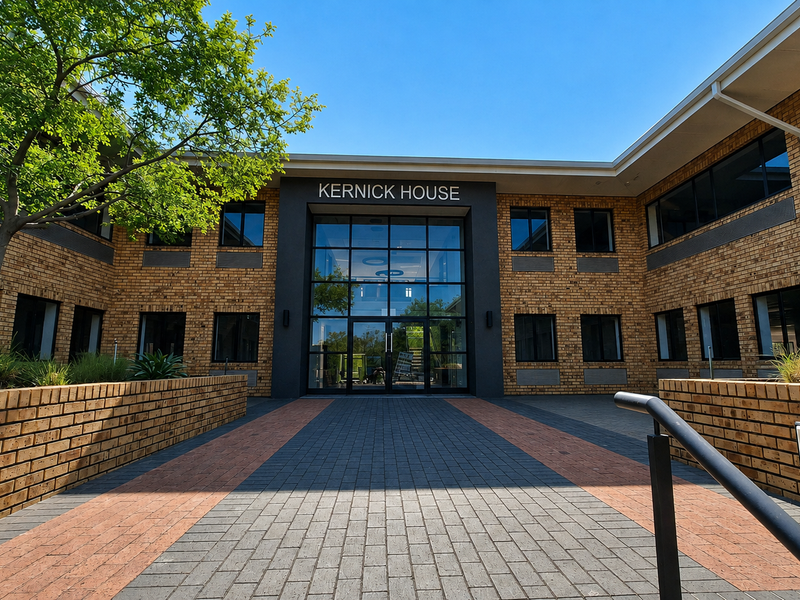The front entrance of Kernick House, featuring a modern glass facade, brick exterior, and a well-maintained paved courtyard approach.