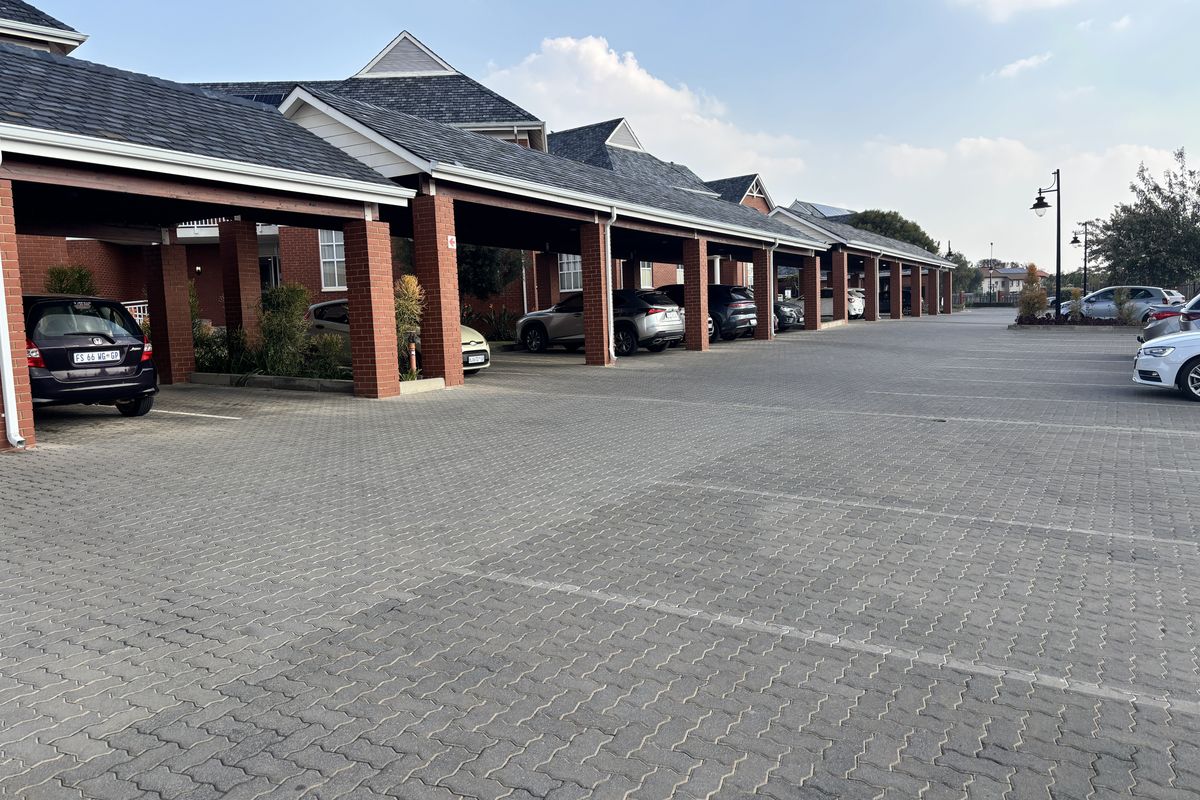 A well-maintained office complex featuring extensive covered parking bays with brick pillars and paved driveway access.