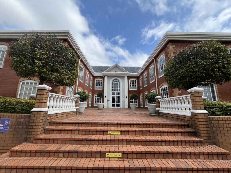 A well-maintained office building entrance featuring a symmetrical brick facade, grand staircase, and classic architectural detailing.