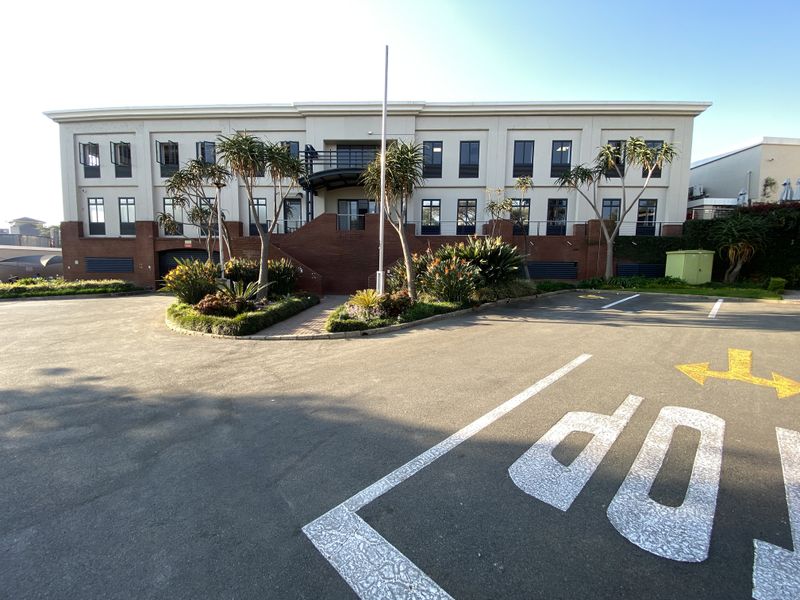 Front exterior view of a professional office building featuring a paved parking area, brick facade, and landscaped garden beds.