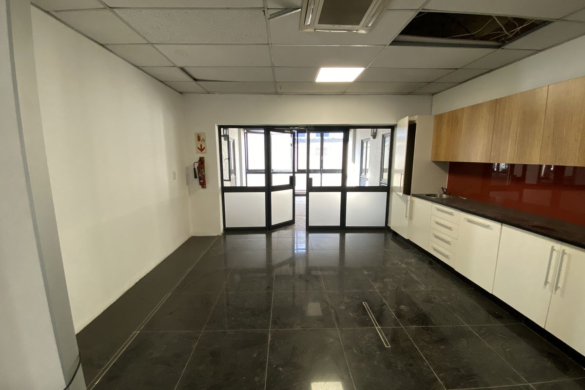 Empty retail kitchen space featuring dark tiled flooring, built-in cabinetry, and glass panel doors, requiring ceiling repairs.