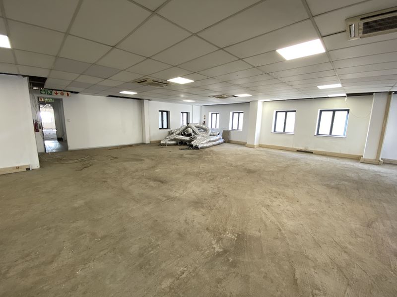 A large, open-plan retail or office space featuring a suspended ceiling, recessed lighting, and unfinished concrete flooring, ready for custom fit-out.
