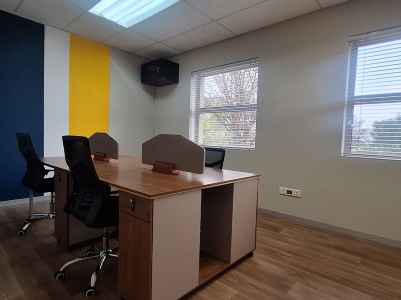 A well-maintained office space featuring laminate flooring, suspended ceilings, and large windows with venetian blinds, providing a bright and professional work environment.