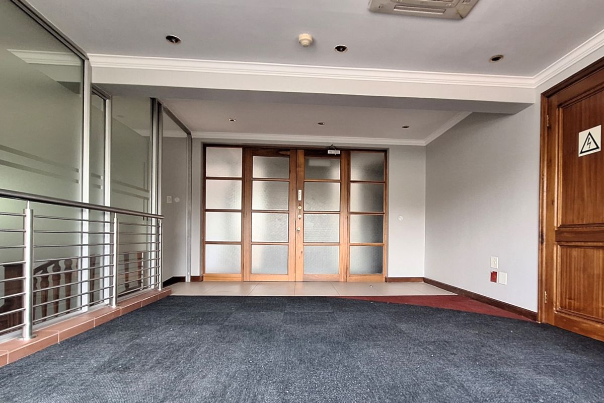 An empty office space featuring frosted glass timber doors, a stainless steel balustrade, and recessed downlighting, providing a professional and versatile work environment.