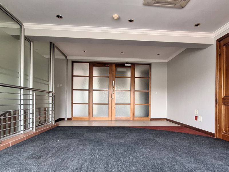 An empty office space featuring frosted glass timber doors, a stainless steel balustrade, and recessed downlighting, providing a professional and versatile work environment.