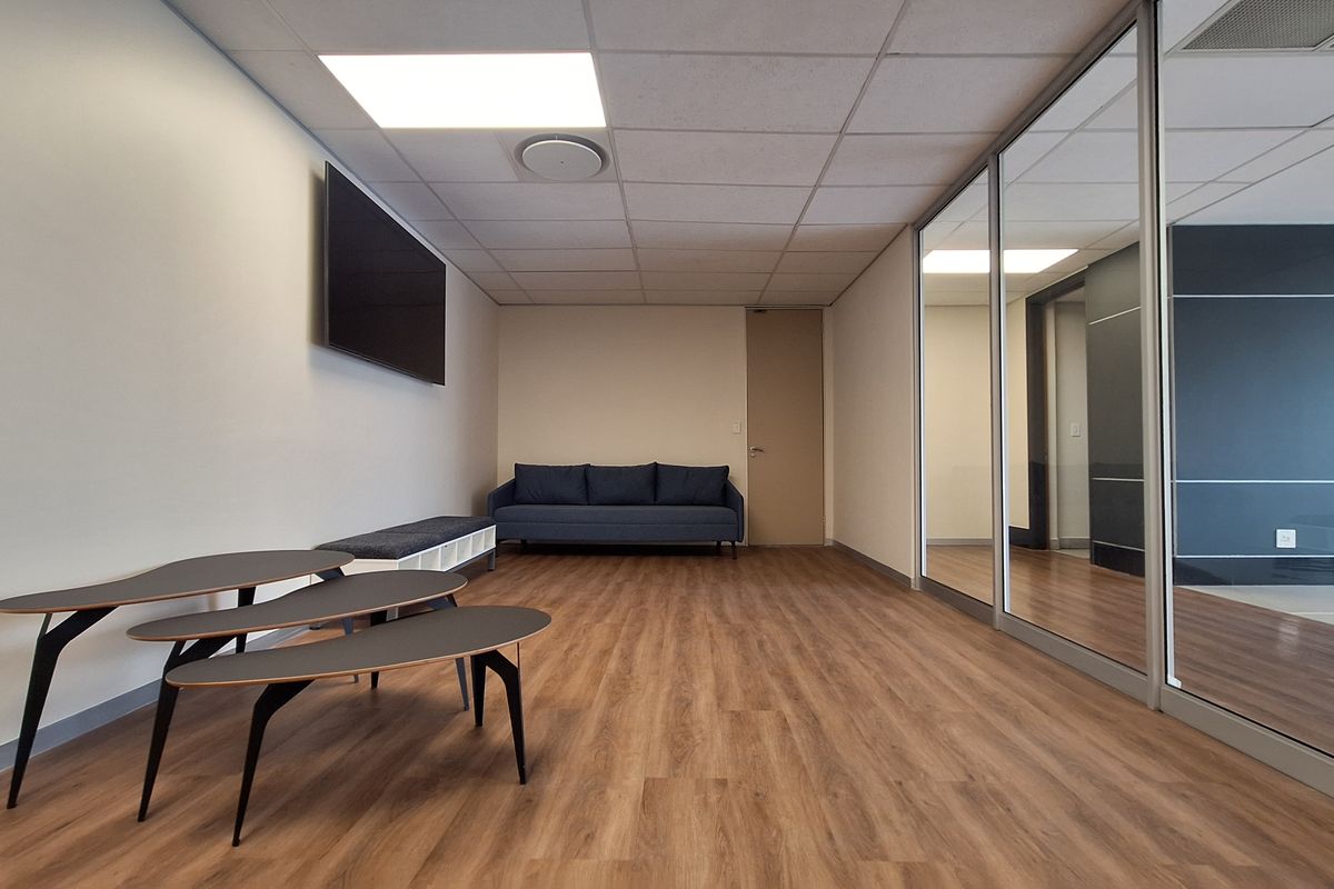 Modern office space featuring laminate flooring, a suspended ceiling with recessed lighting, and a glass partition wall providing a bright, professional work environment.