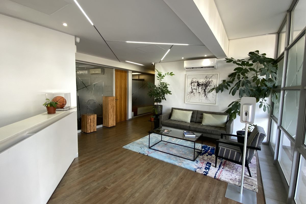 Modern office reception area featuring laminate flooring, recessed linear lighting, split-system air conditioning, and frosted glass partitions for a professional workspace environment.