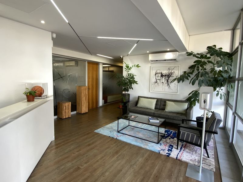 Modern office reception area featuring laminate flooring, recessed linear lighting, split-system air conditioning, and frosted glass partitions for a professional workspace environment.