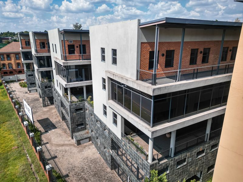 Aerial view of a modern multi-level office complex featuring brick and concrete facades, private balconies, and paved exterior parking areas.