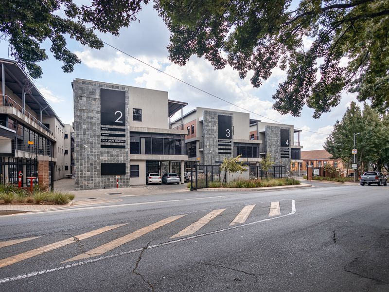A modern multi-unit office complex featuring stone cladding, large glass windows, and secure gated access from the street.