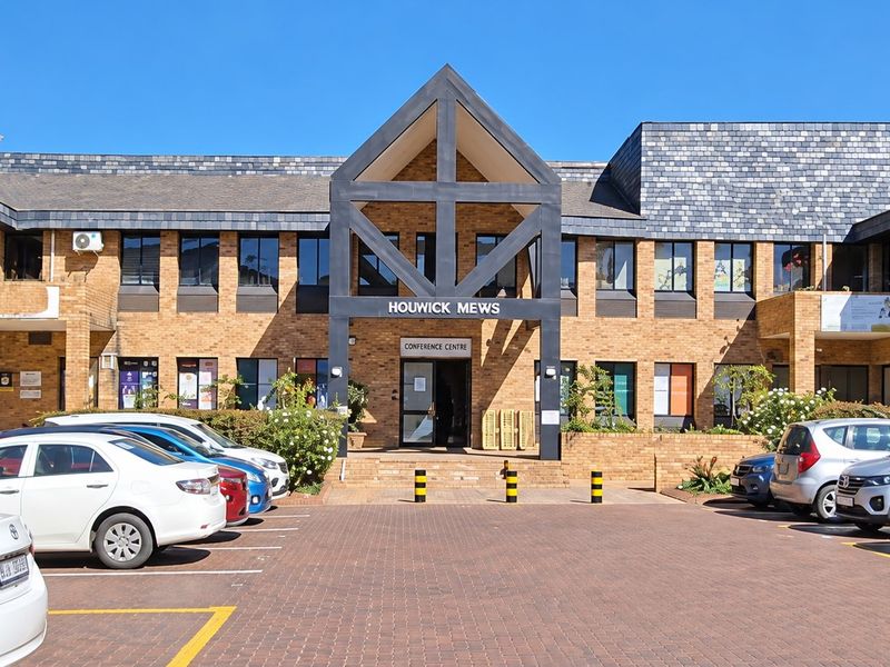 Front elevation of Houwick Mews office complex featuring a brick facade, slate roof, and a paved parking area for visitors and staff.