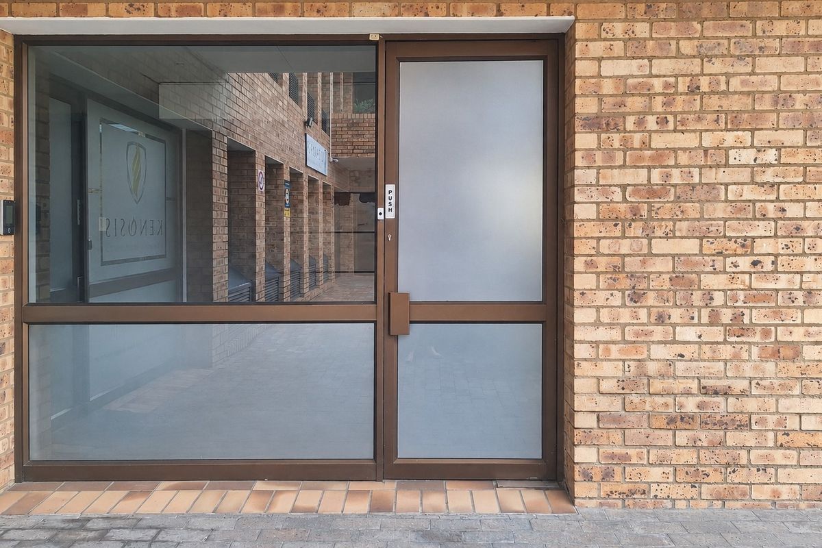A professional office entrance featuring a durable face brick facade and a modern aluminium-framed glass door with frosted privacy panels.