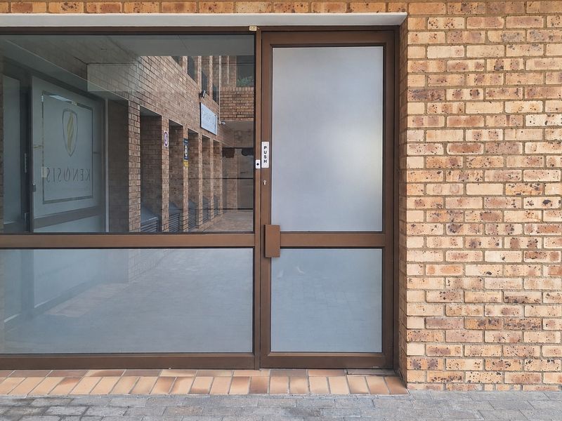 A professional office entrance featuring a durable face brick facade and a modern aluminium-framed glass door with frosted privacy panels.