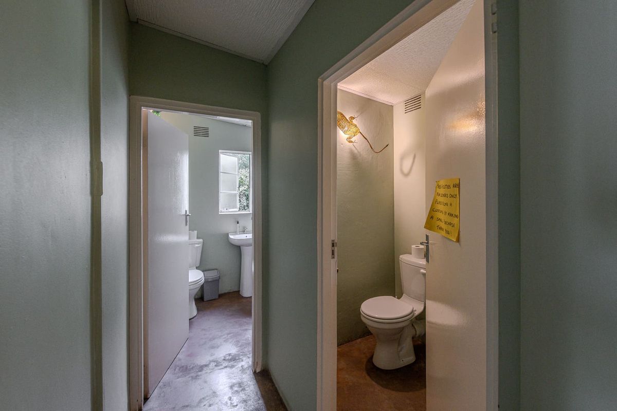 A view of two separate restroom facilities featuring standard toilets and a pedestal basin, showing dated finishes and basic utility infrastructure.